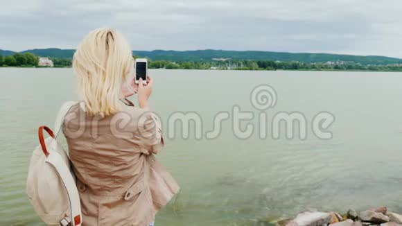 一个女人为一个美丽的湖拍照背面视频的预览图