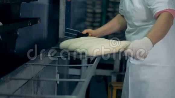 一名工人为银行准备面包并进行表面切割视频的预览图