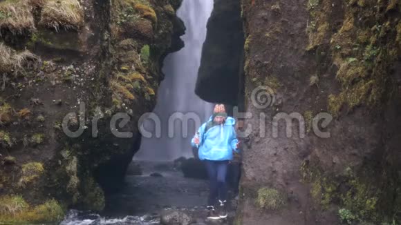 两名年轻游客在冰岛探索强大的瀑布Gljufrabui男人和女人穿着雨衣在雨中行走视频的预览图
