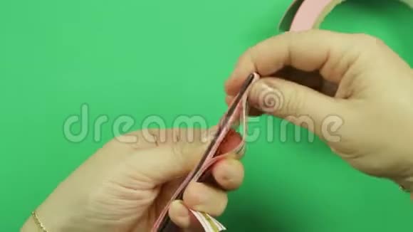 女性的手在绿色背景上包裹着粉红色的丝带图案视频的预览图