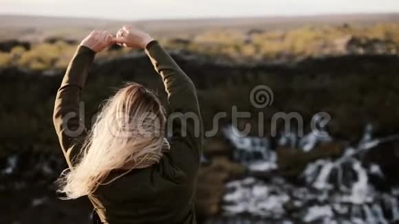 年轻的金发女子站在冰岛的Barnafoss瀑布附近欣赏美丽的风景视频的预览图