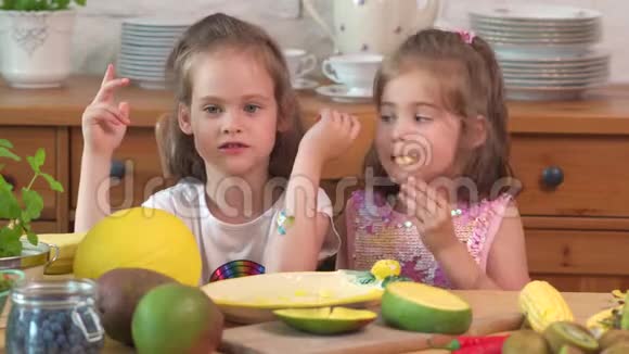 两个可爱的女孩在笑吃一个多汁的黄芒视频的预览图