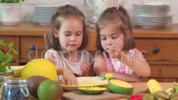 两个可爱的女孩在笑吃一个多汁的黄芒视频的预览图