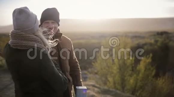 年轻漂亮的夫妇站在桥上聊天休息一下男人和女人在旅行头发在风中飘扬视频的预览图