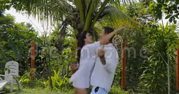 在别墅附近的热带花园里女人跳过男人的一对情侣拥抱亲吻视频的预览图