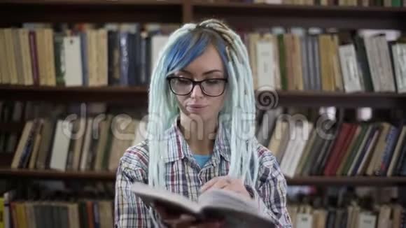 戴眼镜的嬉皮士女人在图书馆看书的肖像视频的预览图