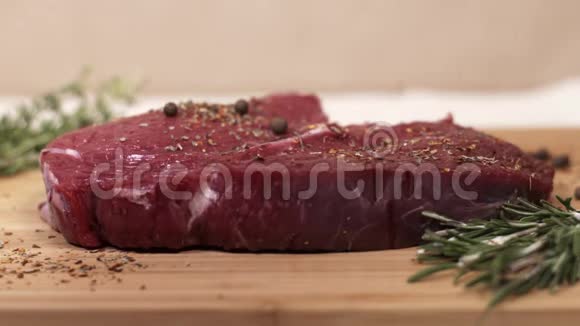 在桌子上放一大块生红肉和迷迭香和香料视频的预览图