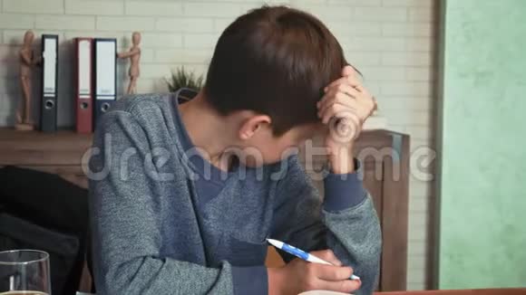 一个疲惫的男孩在书桌上做作业视频的预览图
