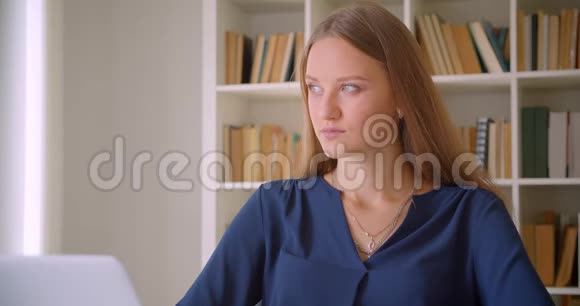 一位年轻的高加索女商人正坐在办公室的办公桌前看着镜头微笑的特写照片视频的预览图
