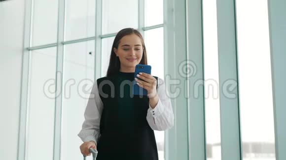 通勤车上的女商人在火车站或飞机上拿着手提行李走路时在智能手机上讲话视频的预览图