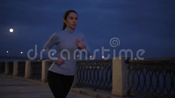 一个穿着运动服的年轻女孩在月光下的海滨慢跑2这名运动员从事体育运动视频的预览图