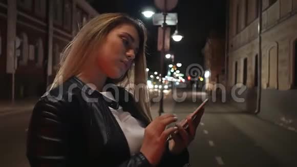 城市里夜里的金发女孩用电话期待有人视频的预览图