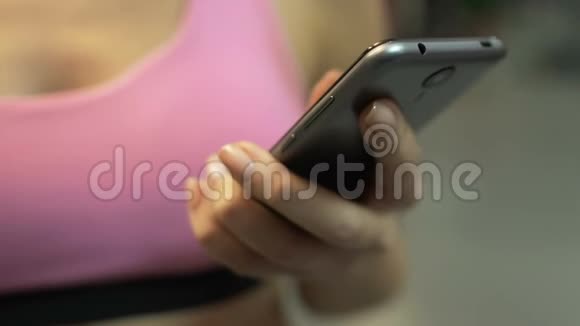 适合女孩向下滚动手机屏幕在锻炼前选择应用程序视频的预览图