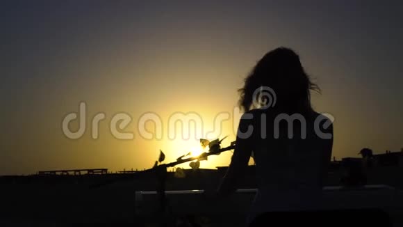 日落时分女人用数码钢琴演奏浪漫的音乐漂亮女孩在舞台上和太阳一起唱歌视频的预览图
