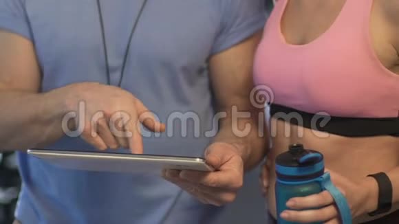 培训人员向女性客户展示平板电脑屏幕从运动瓶中获取饮用水视频的预览图