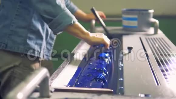 一个人正把蓝色的油漆放在一个印刷机的托盘里视频的预览图