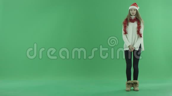 戴着圣诞帽的漂亮女性展示了她身边的一些东西并讲述了这件事背景上的色度键视频的预览图