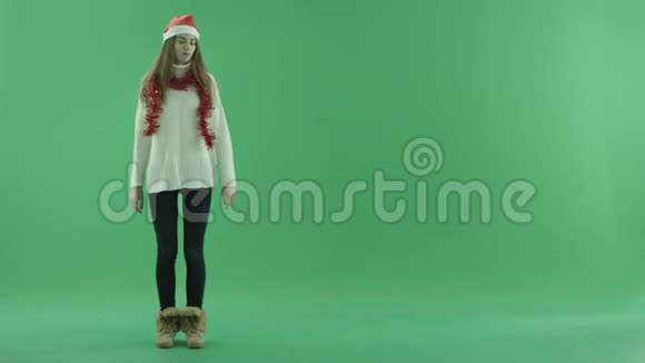圣诞帽里迷人的年轻美女展示了她身边的一些东西并讲述了这件事背景上的色度键视频的预览图