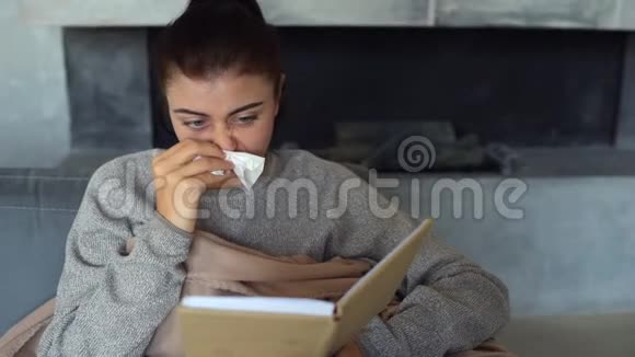 精疲力竭的年轻女子用纸巾吹红鼻子视频的预览图
