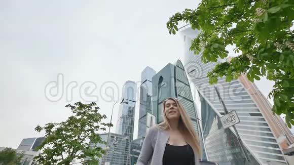 金发女孩心情好在高楼大厦和市中心摩天大楼的背景下跳跃视频的预览图