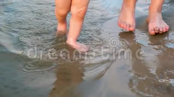 宝贝沿着河岸走第一步在两边泼水和他妈妈一起走腿特写镜头慢慢视频的预览图