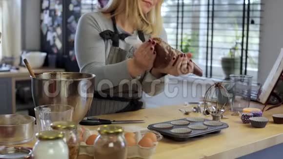 金发女郎把糕点袋里的面团放进纸杯里放在厨房的烤盘里视频的预览图