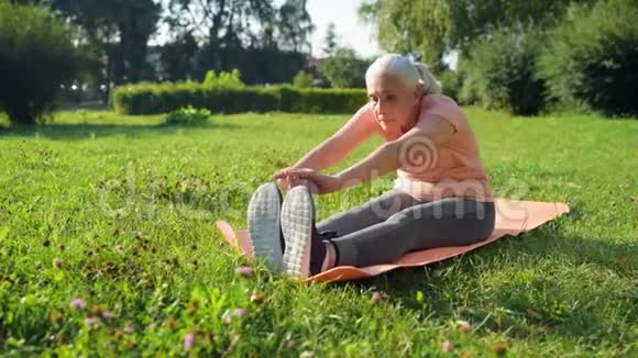 漂亮的老妇人在运动垫上做热身运动视频的预览图