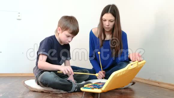 妈妈和儿子坐在地板上的房间里玩木琴视频的预览图