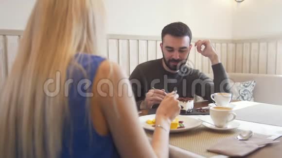 年轻的白种人男人在女人面前试着在咖啡馆吃甜点视频的预览图