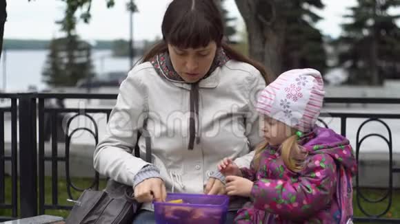 年轻的女人和她的小女儿在公园秋天吃三明治视频的预览图