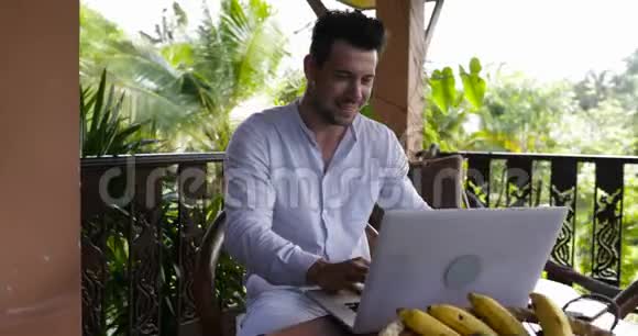 喜笑颜开的人在露台上使用笔记本电脑偶然的商人在电脑打字外门上工作视频的预览图