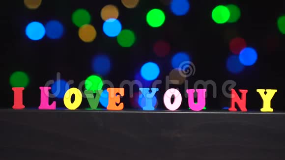 五颜六色的文字我爱你纽约从彩色的木制字母前面抽象模糊的灯光背景视频的预览图