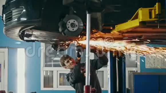 汽车汽车服务工人在车辆底部用圆锯打磨金属结构视频的预览图