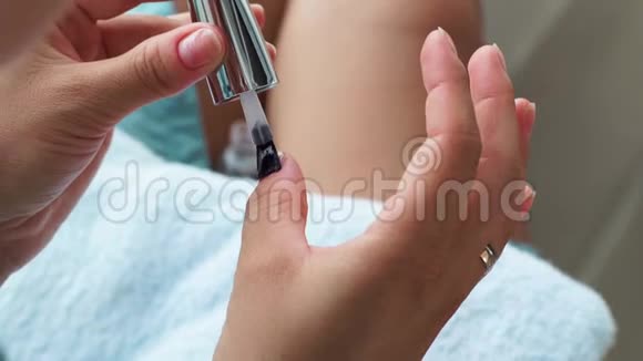 女性在家修指甲时涂基础指甲油使用美甲漆进行治疗美甲的女性视频的预览图