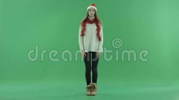 可爱的年轻女士戴着圣诞帽看上去不知所措惊叹不已背景色钥匙视频的预览图