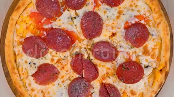 把意大利腊肠披萨切在桌子上的木板上特写俯视图视频的预览图