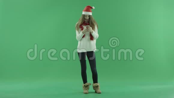 戴着智能手机的圣诞帽戴着彩色钥匙的年轻金发美女视频的预览图