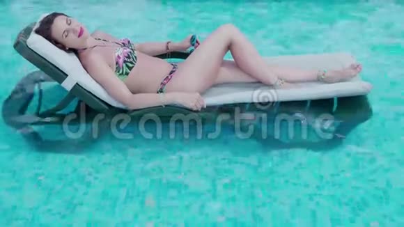 一个炎热的夏天年轻漂亮的女人正在游泳池旁休息4K视频的预览图
