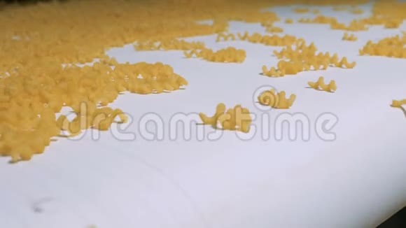 一堆黄色螺旋状的通心粉沿传送带移动意大利面通心粉面条意大利面的生产视频的预览图
