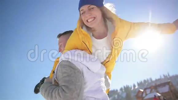英俊的男人把女孩骑在肩膀上在蓝天背景上旋转她浪漫的情侣正在享受温暖视频的预览图