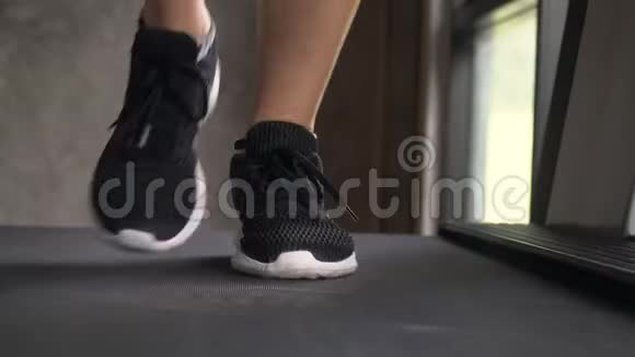 年轻女子在健身房跑步机上慢跑脚踝感觉疼痛正面向上看视频的预览图