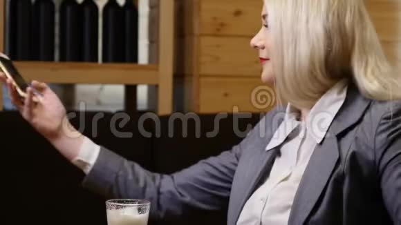 女商人坐在咖啡馆的桌子旁做自拍视频的预览图
