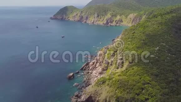 绿色的山岩石悬崖和船只航行在蓝色的海洋鸟瞰无人驾驶山崖的美丽景观视频的预览图