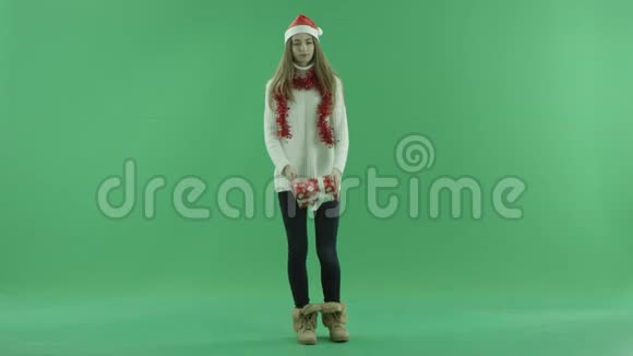 戴着圣诞帽的迷人年轻女子试图意识到她的圣诞礼物里有什么背景上的色度键视频的预览图