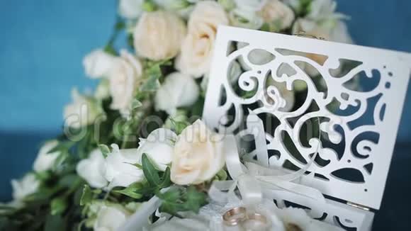 婚礼的概念婚礼戒指放在一个手工制作的木箱里周围是绿松石背景上的花视频的预览图