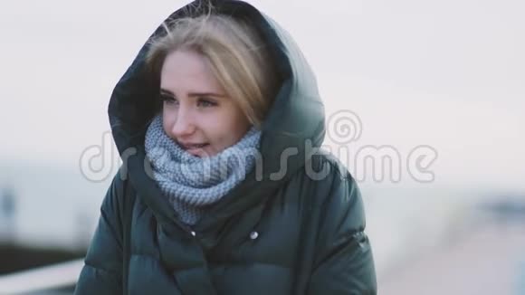 秋日寒冷的户外穿着暖和的衣服的迷人年轻女子的肖像视频的预览图