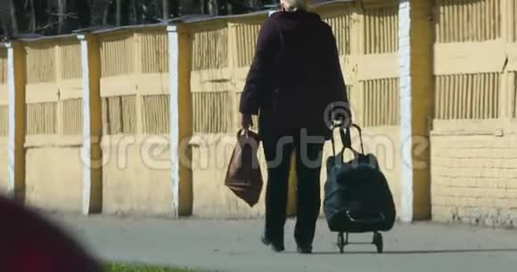 带着购物袋的女人沿着人行道走到后景视频的预览图