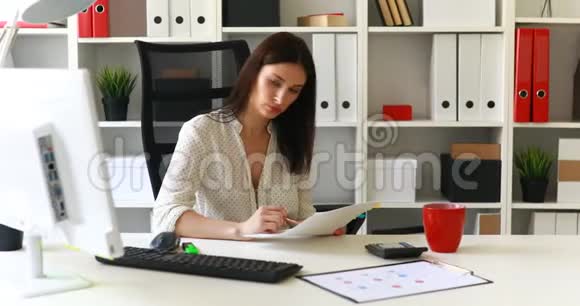 女商人坐在办公室椅子上看文件视频的预览图
