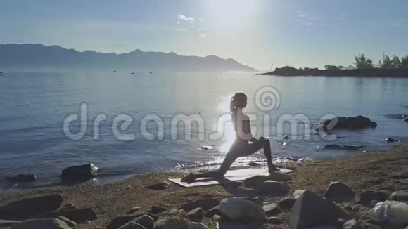 侧视女孩站在瑜伽对抗上升的太阳反射视频的预览图