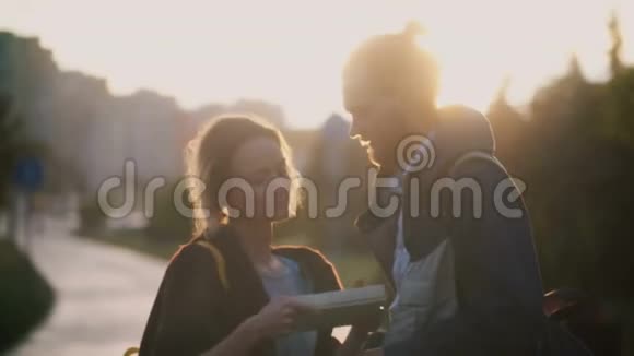 日落时分年轻的幸福夫妇在市中心散步漂亮的女人用男人的礼物打开盒子视频的预览图